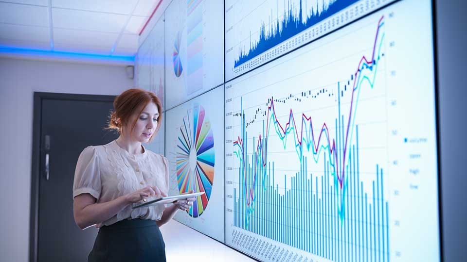 Businesswoman studying graphs on screen